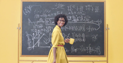 a woman standing in front of a blackboard with writing on it