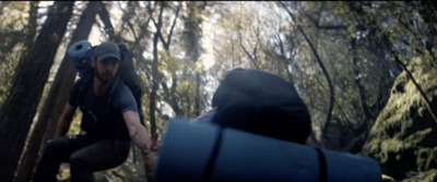 a man riding a skateboard through a forest