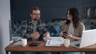 a man and a woman sitting at a table looking at their cell phones