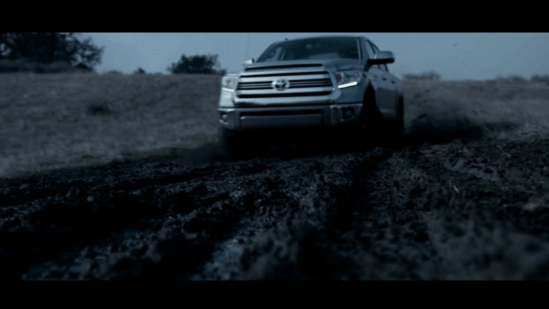 a silver truck driving down a dirt road