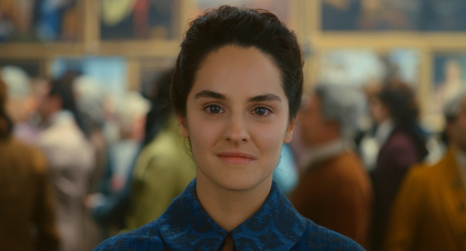 a woman with a blue shirt and tie standing in front of a group of people