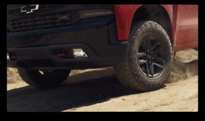 a red truck driving down a dirt road