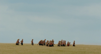 a group of people walking across a grass covered field