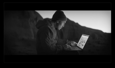 a man sitting on a rock using a laptop computer