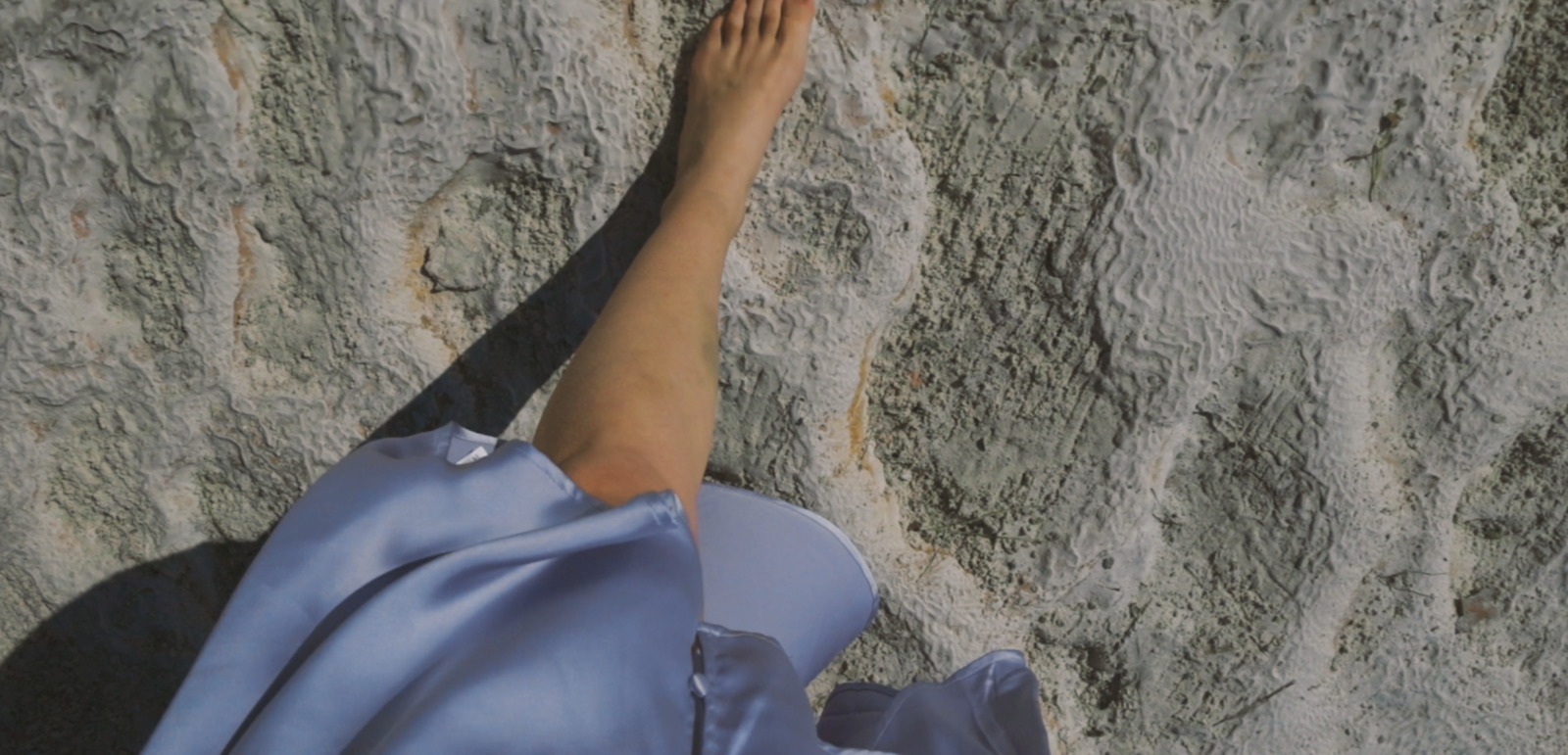 a woman's foot in a blue dress on a rock