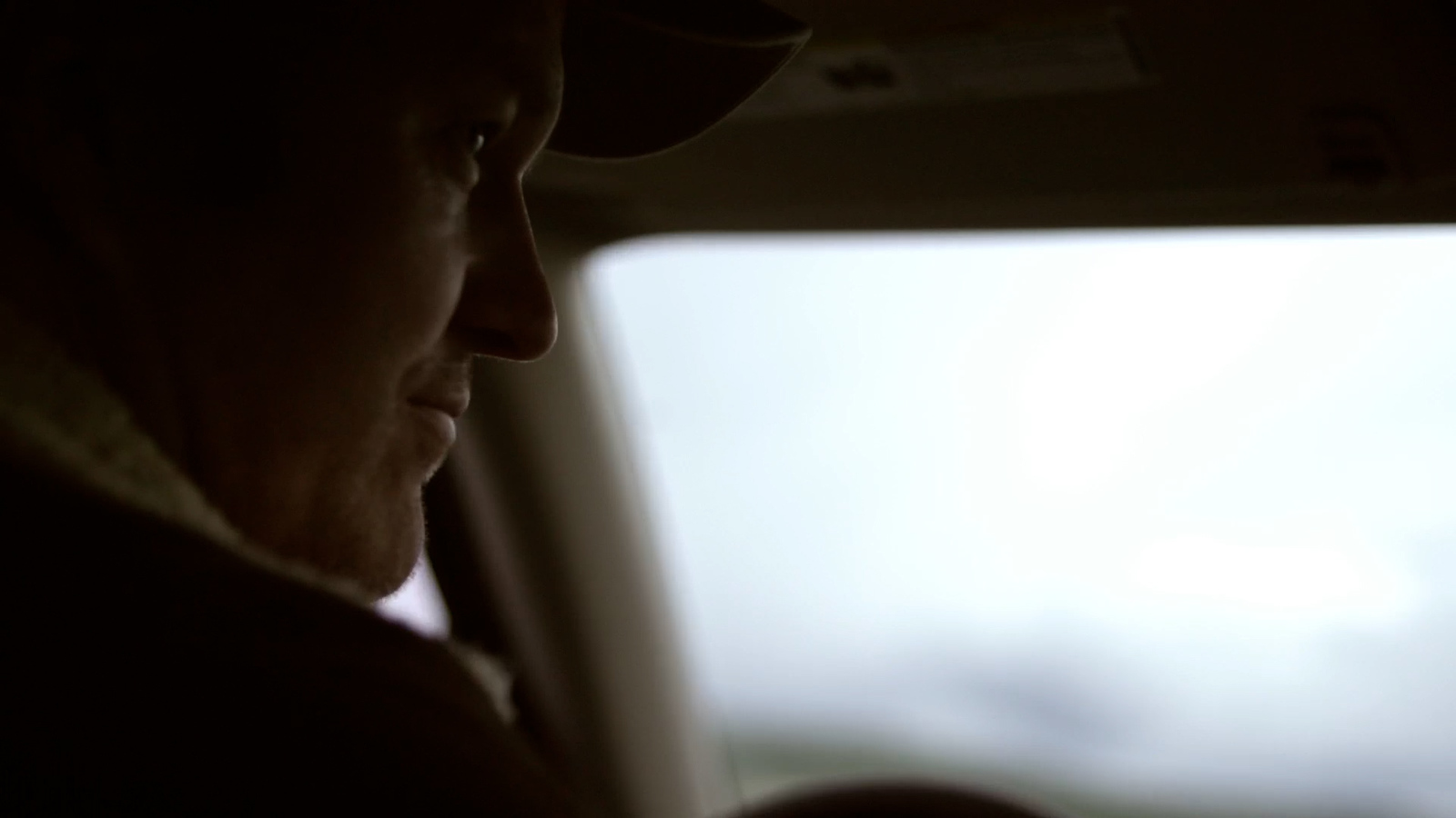 a man sitting in a car looking out the window