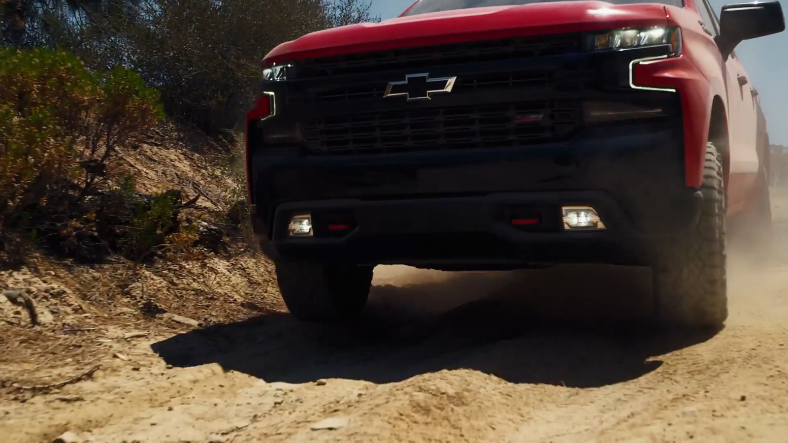 a red truck driving down a dirt road