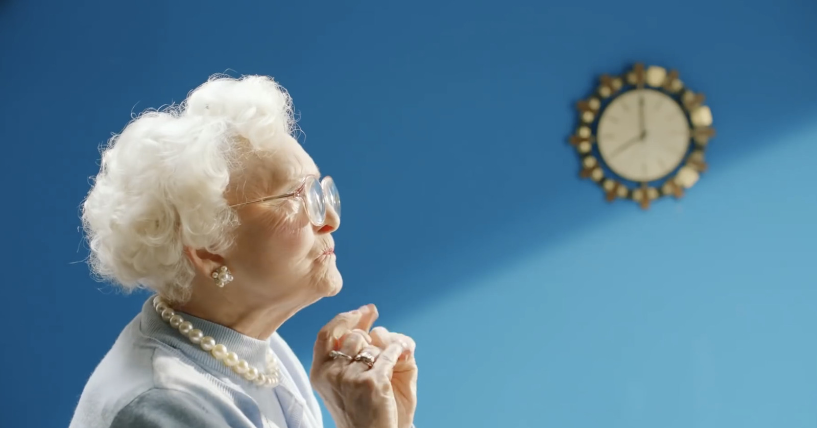 a woman in glasses is looking up at a clock