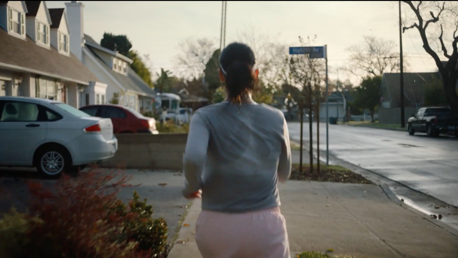 a woman walking down a sidewalk next to a street