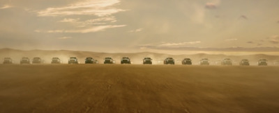 a group of trucks driving down a dirt road