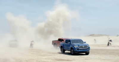 a couple of trucks driving down a dirt road