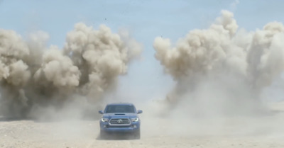 a blue truck driving down a dirt road