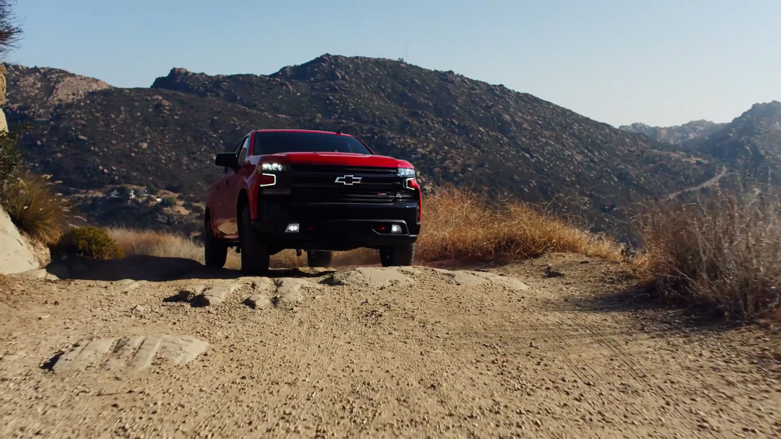 a red truck is parked on a dirt road