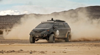 a vehicle driving on a dirt road in the desert