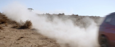 a red car driving down a dirt road