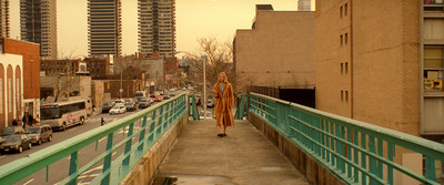 a woman walking across a bridge in a city