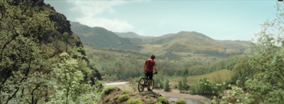 a man standing on top of a mountain next to a river