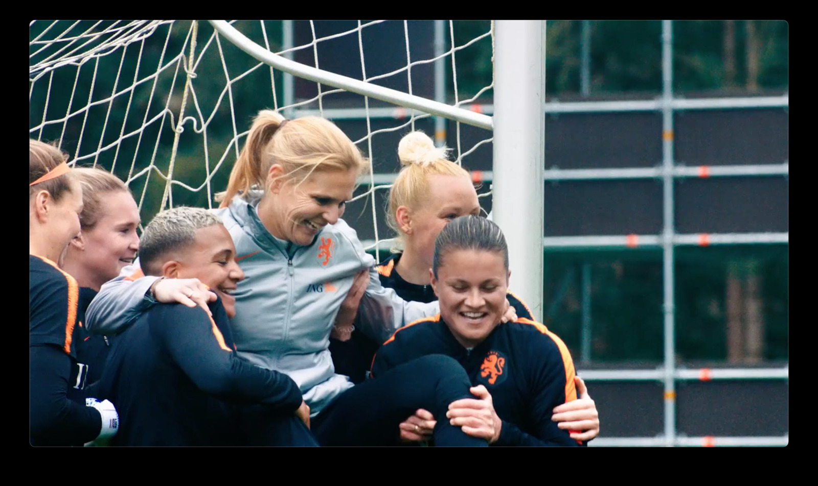 a group of young women standing next to each other in front of a soccer net