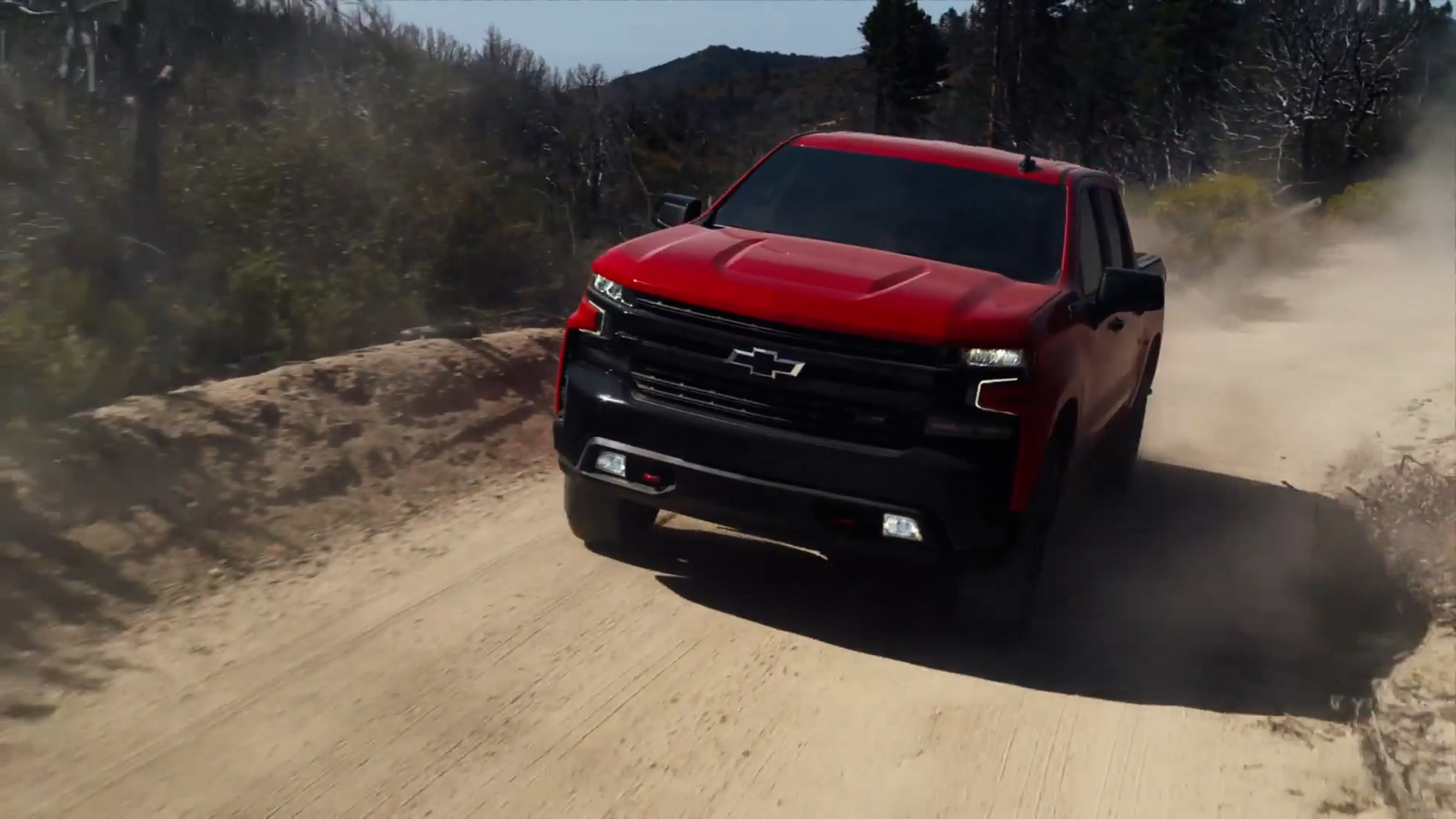 a red truck driving down a dirt road