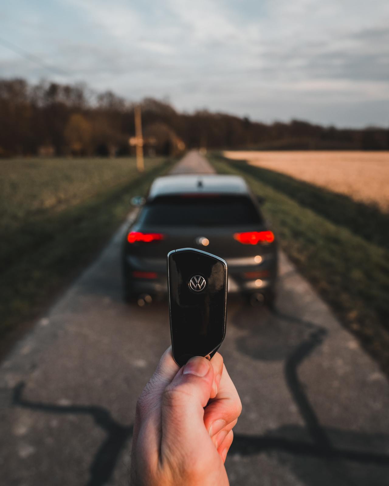 a hand holding a remote control in front of a car