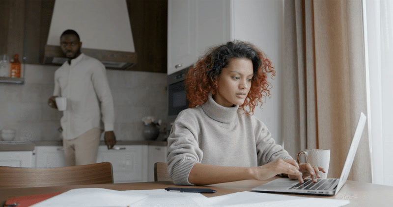 a woman sitting at a table using a laptop computer