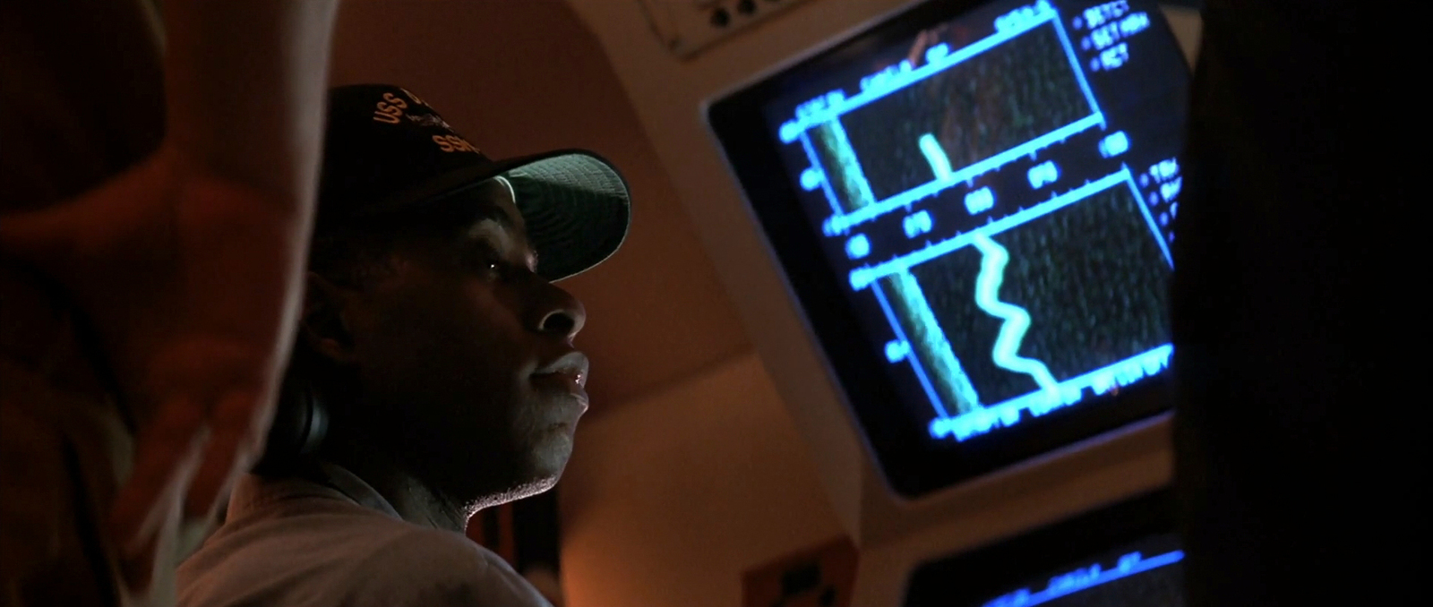 a man in a baseball cap looking at a computer screen