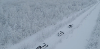 a group of cars driving down a snow covered road