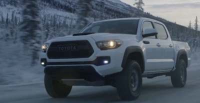 a white toyota truck driving down a snowy road