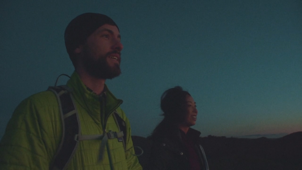 a man with a beard and a backpack standing next to a woman