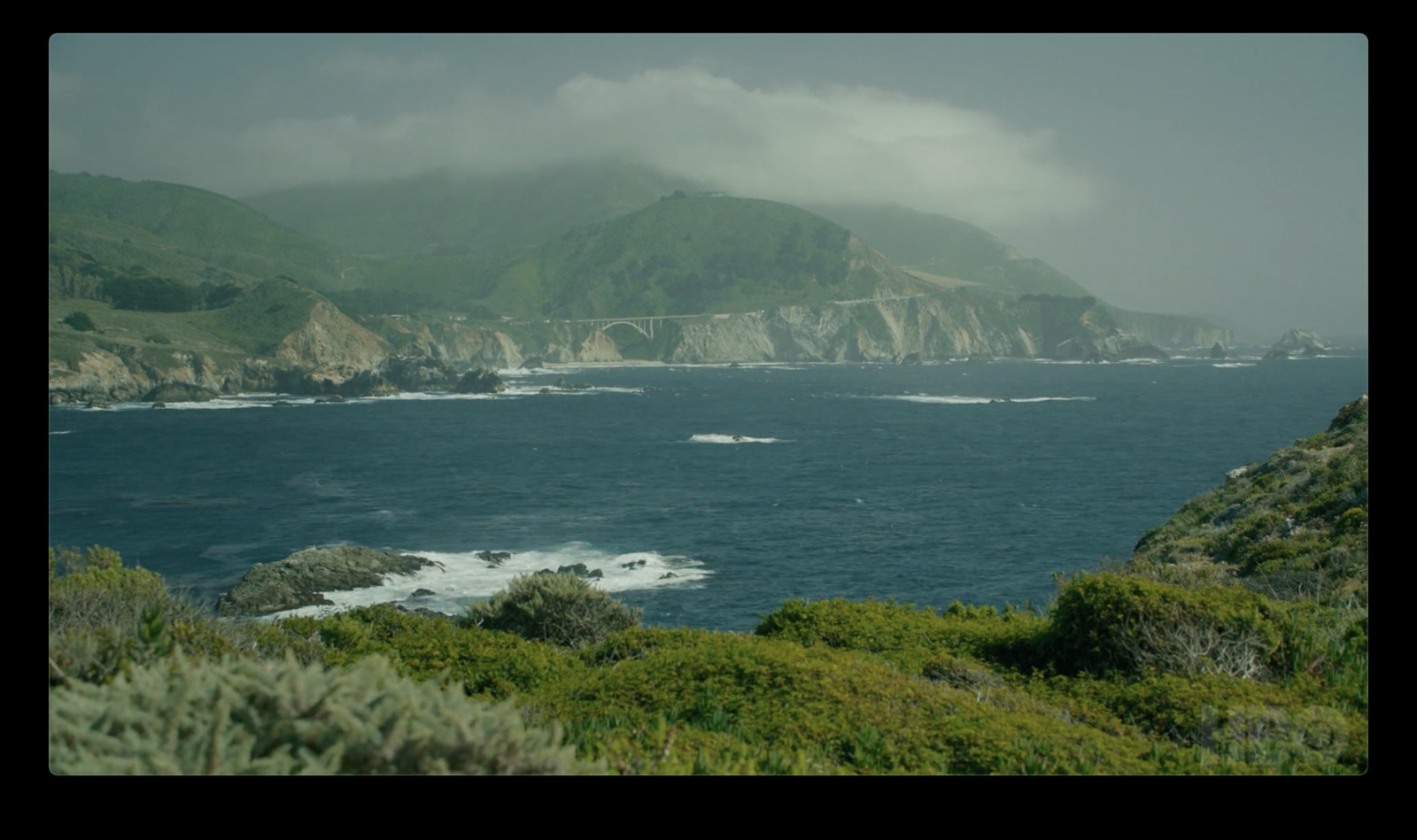 a large body of water surrounded by a lush green hillside