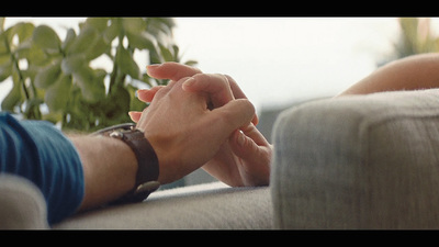 two people holding hands while sitting on a couch