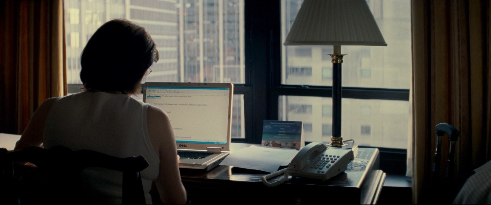 a woman sitting at a desk in front of a laptop computer