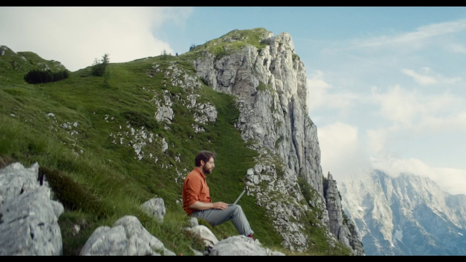 a man sitting on top of a lush green hillside