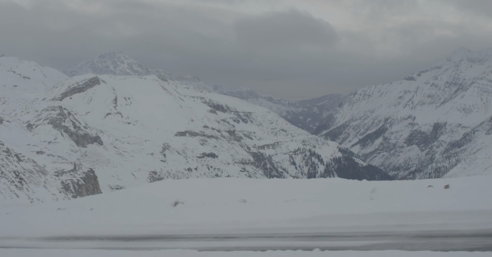 a snow covered mountain range with a cloudy sky