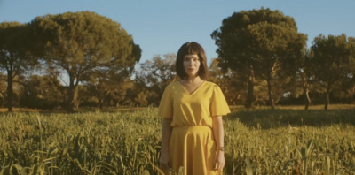 a woman in a yellow dress standing in a field