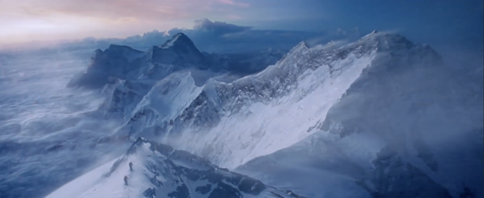 a very tall mountain covered in snow under a cloudy sky