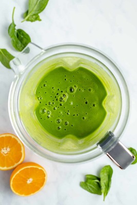 a green smoothie in a glass with orange slices