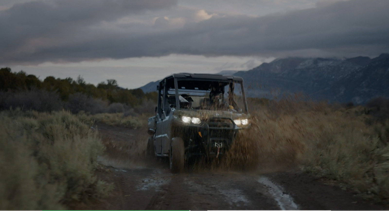 a vehicle driving down a dirt road in the middle of a field