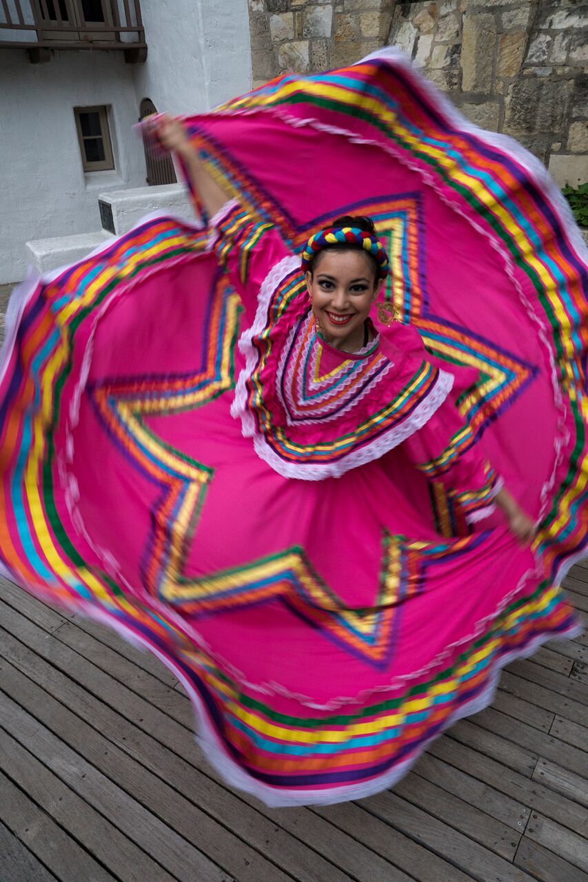 a woman in a colorful dress dancing on a deck