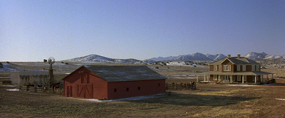 a red barn in a field with mountains in the background