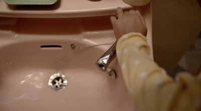 a child is washing their hands in a pink sink