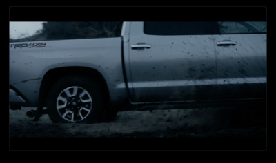 a silver truck parked in a field with trees in the background