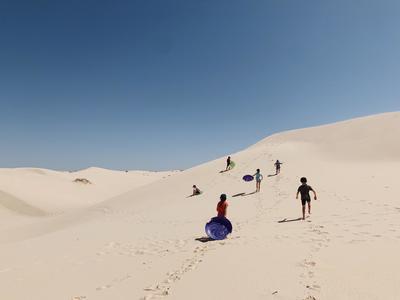 a group of people walking up a sand dune