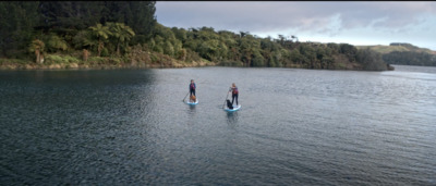 a couple of people riding paddle boards on a lake