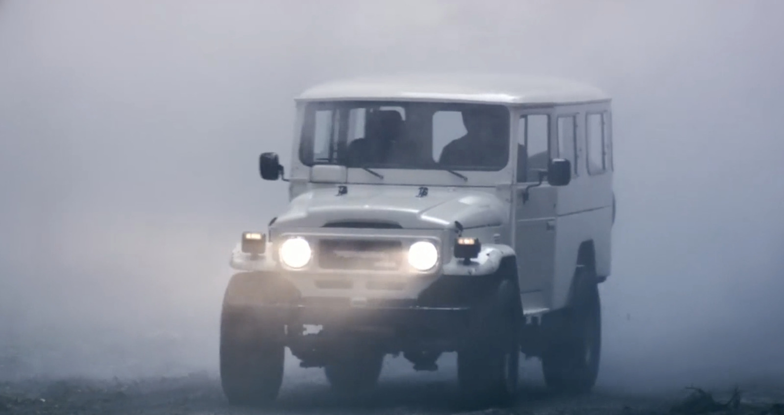 a white truck driving down a foggy road