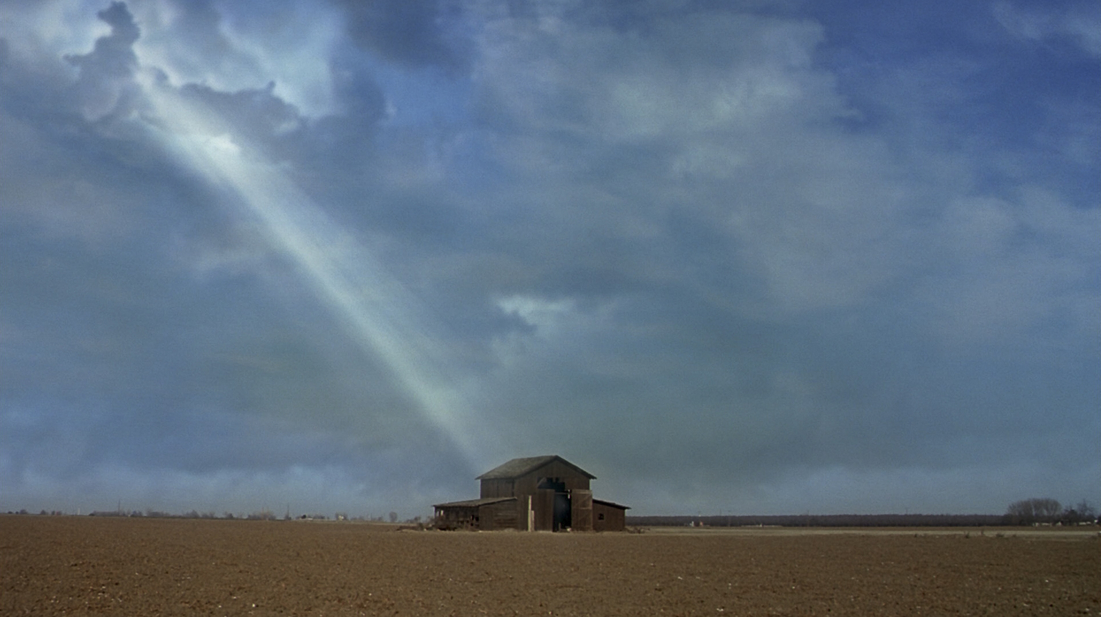 a barn in a field under a cloudy sky