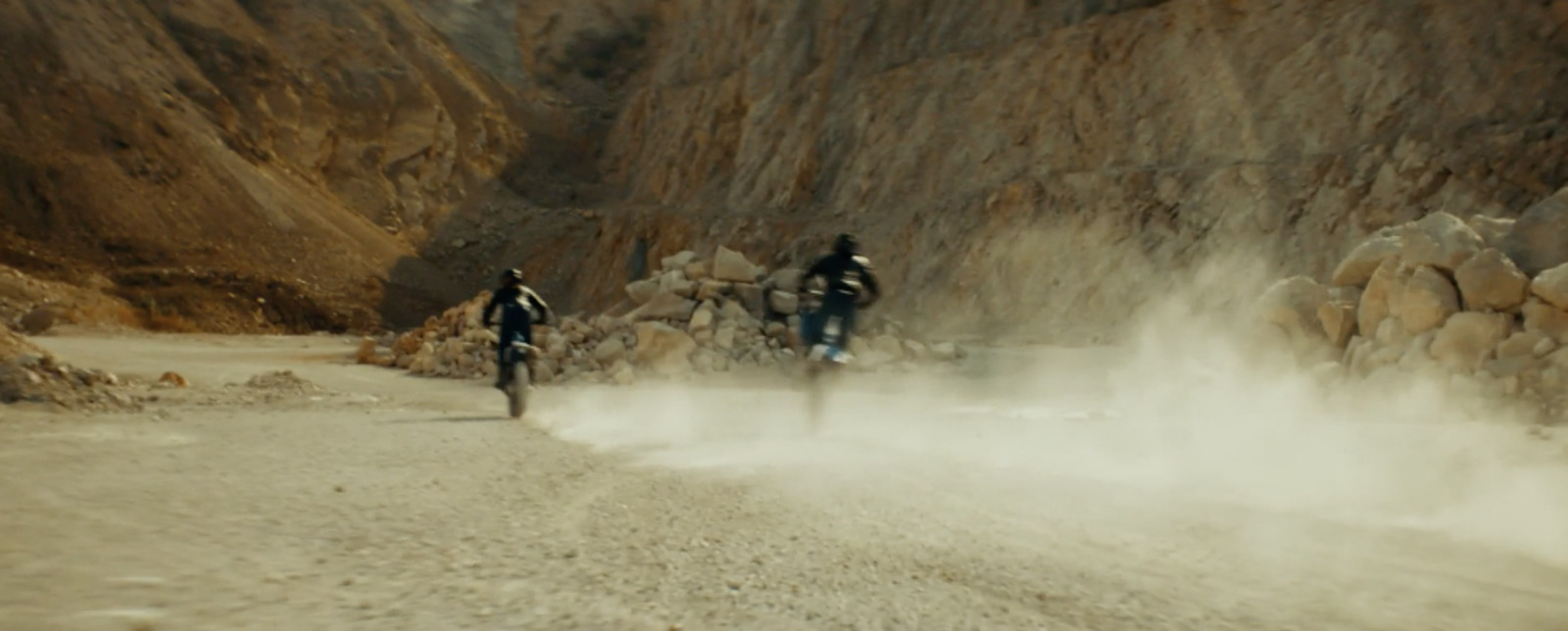 a couple of people riding bikes down a dirt road