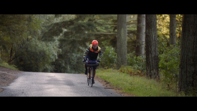 a person riding a bike down a road in the woods