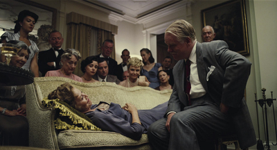 a group of people watching a man laying on a couch