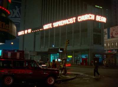 a red truck driving down a street next to a tall building